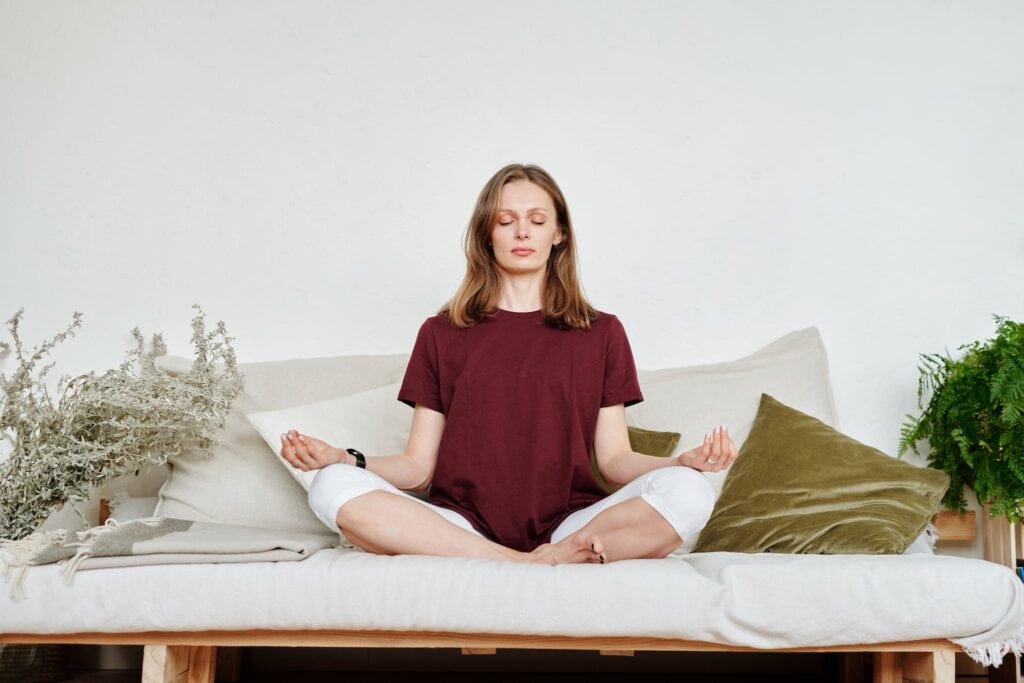 Mujer en Remera Roja Sentada en Sofa Meditando