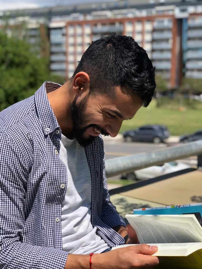 Hombre con Camisa en Parque Riendo Con Libro